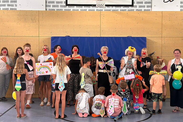 Kinder der Mittagsbetreuung der Grundschule Erpfting überreichen gemeinsam mit ihren Betreuerinnen, den Praktikantinnen und Schulreferentin Margit Däubler den Spendenscheck über 500 Euro an KlinikClown „Dr. Pfuschl“. Foto: Nele Birner