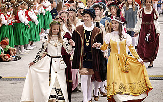 Bunte historische Kostüme beim Ruethenfest-Einzug Landsberg: Mädchen in grünen Trachten und Jungen in Ritterkleidern laufen Händchen haltend über den Platz.