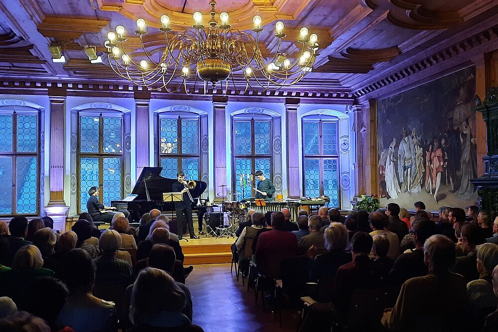 Klavier- und Streichquartett spielt bei beleuchtetem Konzert im Festsaal des Historischen Rathauses Landsberg: Wandfresken, Kronleuchter und volles Publikum in historischem Ambiente.