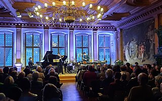 Klavier- und Streichquartett spielt bei beleuchtetem Konzert im Festsaal des Historischen Rathauses Landsberg: Wandfresken, Kronleuchter und volles Publikum in historischem Ambiente.