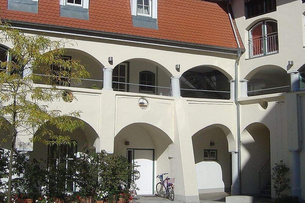 Renaissance-Innenhof des Färberhofs Landsberg am Lech mit Arkadengängen, rotem Dach und Fahrrad, sonniger Tag, CC-BY-SA.