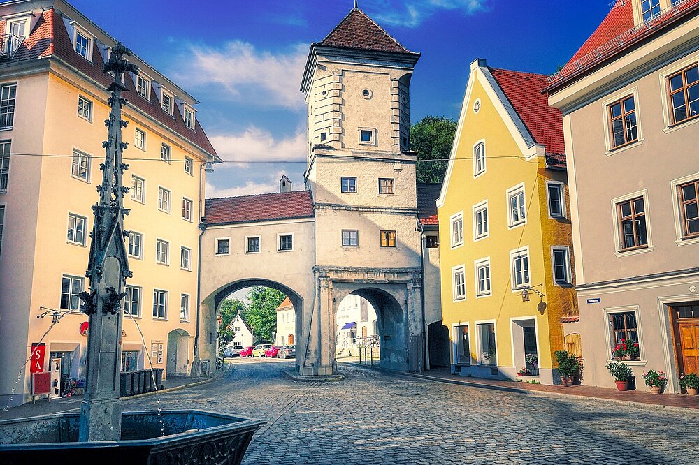 Sandauer Tor Landsberg am Lech, historisches Stadttor mit gelbem Haus auf Kopfsteinpflaster, sonniger Himmel, Foto Fietz, CC-BY-NC.