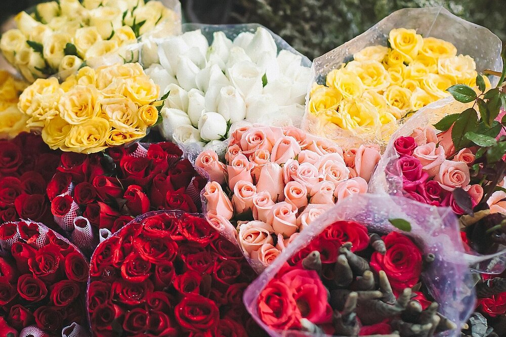 Bunter Blumenstand mit gelben, weißen, roten und rosafarbenen Rosen beim Markt in Landsberg am Lech. 