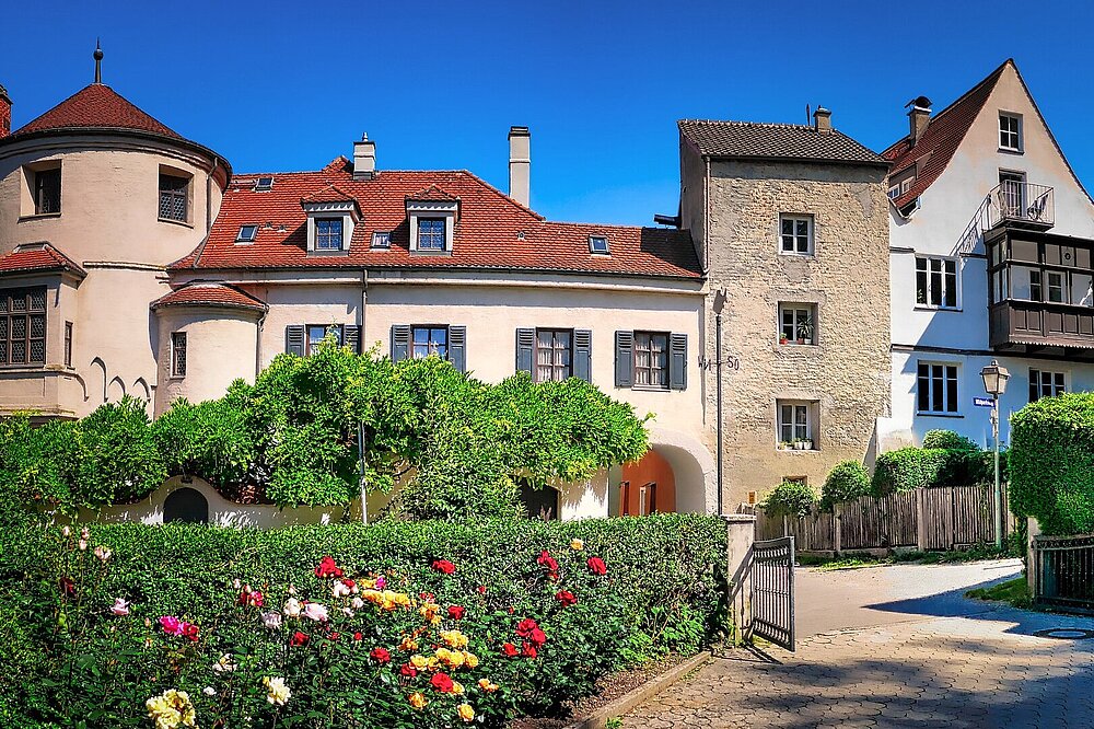  Historisches Klösterl mit rundem Turm und Fachwerkhäusern in Landsberg am Lech, umgeben von blühenden Rosenhecken, sonniger Tag, Foto von Fietz, CC-BY-SA.